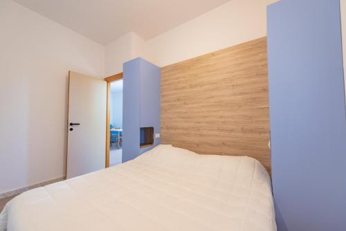 a bedroom with a white bed and a wooden wall at Club del Sole Stork Family Collection in Giulianova