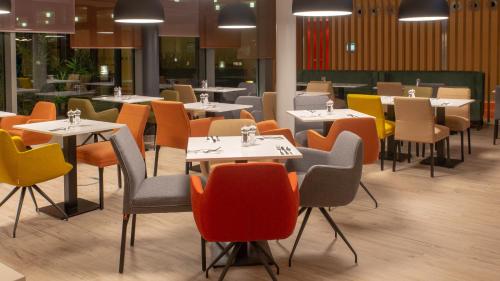 a dining room with tables and chairs and tablesktop at Holiday Inn Berlin Airport - Conference Centre by IHG in Schönefeld