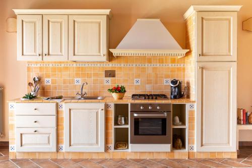 a kitchen with white cabinets and a sink at Podere Caprarecce Bilocale in Talamone