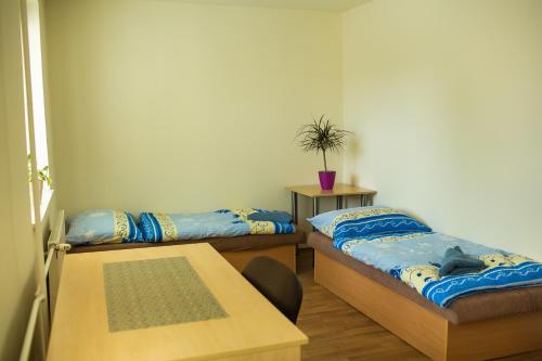 Habitación con 2 camas y mesa. en Danubius Szálló en Komárno
