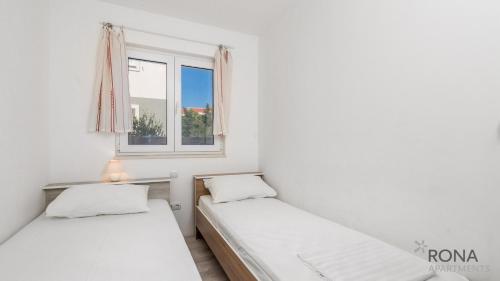 2 Betten in einem Zimmer mit Fenster in der Unterkunft Rona Apartments Zlatko in Šimuni