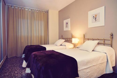 メリダにあるApartamentos Turísticos Ceresのベッド2台と窓が備わるホテルルームです。