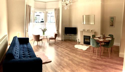 a living room with a blue couch and a table at Mostyn Villa Free Private Parking in Llandudno