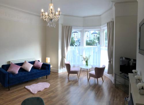 a living room with a blue couch and a table at Mostyn Villa Free Private Parking in Llandudno