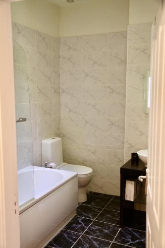 a bathroom with a tub and a toilet and a sink at Mostyn Villa Free Private Parking in Llandudno