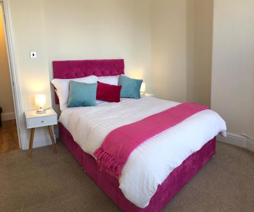 a bedroom with a large bed with a red headboard at Mostyn Villa in Llandudno