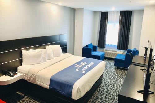 a hotel room with a large bed and blue chairs at Days Inn & Suites by Wyndham Horn Lake - Memphis Graceland in Horn Lake