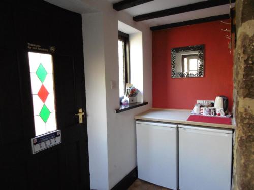 a kitchen with red walls and a counter with a window at The Old Mill and Cottage in Matlock