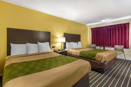 2 Betten in einem Hotelzimmer mit gelben Wänden in der Unterkunft Econo Lodge in Saint George