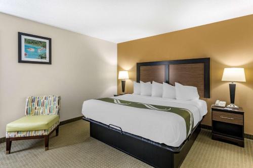 a hotel room with a large bed and a chair at Quality Inn in Ocoee