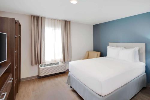 a bedroom with a large white bed and a window at WoodSpring Suites Plano - North Dallas in Plano