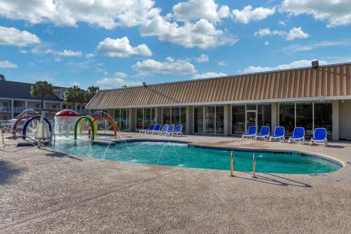 a pool with a water slide and chairs in front of a building at Quality Inn & Suites in Pawleys Island