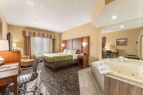 a hotel room with a bed and a tub and a bedroom at Quality Inn & Suites Hendersonville - Flat Rock in Flat Rock