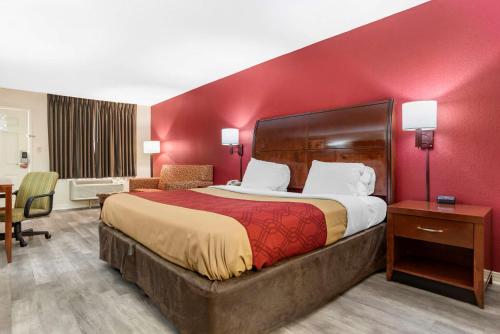 een hotelkamer met een groot bed met een rode muur bij Econo Lodge Pearl - Jackson in Pearl