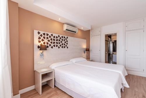 マルベーリャにあるPuerto Azul Marbellaの白い大型ベッドと壁が備わるベッドルーム1室が備わります。