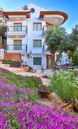 a building with purple flowers in front of it at Çınarlar Apart Hotel KAŞ in Kas