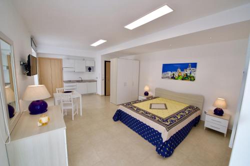 a bedroom with a bed and a table and a kitchen at Domus Le Ceramiche in Grottaglie