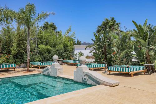 a pool with blue and white benches and trees at Maison San Alfredo B&B in El Puig