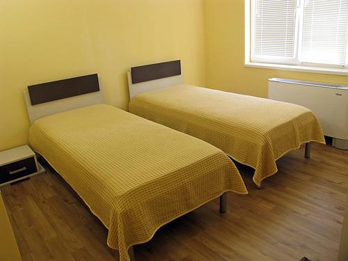 2 letti con lenzuola gialle in una stanza di Хотел Хисаря a Haskovo