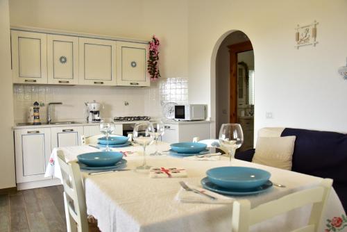 una cocina con una mesa con platos y copas de vino en Casa vacanza Lentisco D Sardegna Ogliastra, en Tertenìa