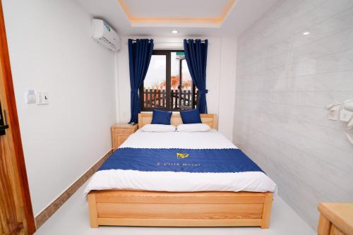 a small bedroom with a bed with blue curtains at S Villa Hotel in Da Thanh
