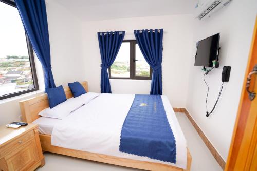 a bedroom with a bed with blue curtains and a tv at S Villa Hotel in Da Thanh