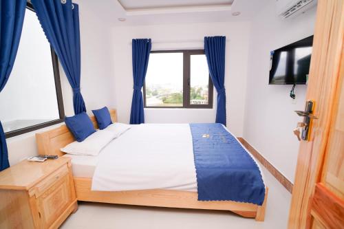 a bedroom with a bed with blue curtains and a tv at S Villa Hotel in Da Thanh
