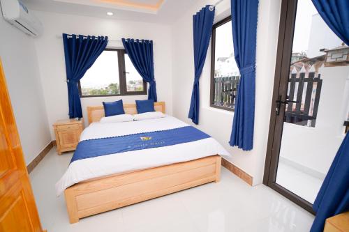 a bedroom with a bed with blue curtains at S Villa Hotel in Da Thanh