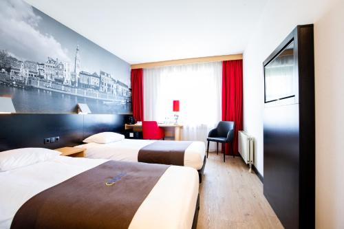 een hotelkamer met 2 bedden en een bureau bij Bastion Hotel Breda in Breda