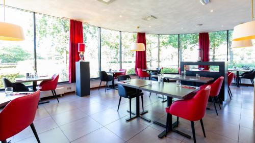 ein Restaurant mit roten Stühlen, Tischen und Fenstern in der Unterkunft Bastion Hotel Breda in Breda