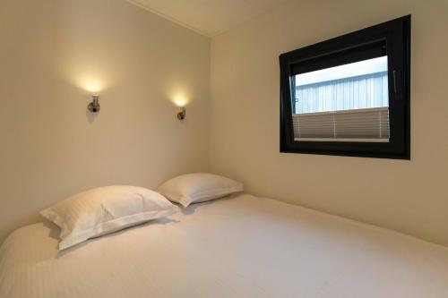 a bedroom with a bed with two pillows and a window at Houseboat-Oostende in Ostend