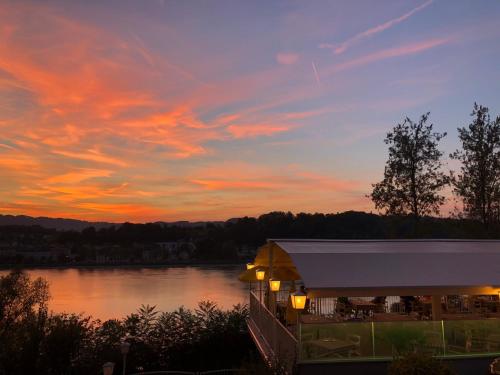 a sunset over a lake with a building in front at Hotel-Restaurant Faustschlössl in Feldkirchen an der Donau