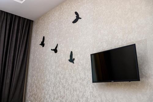 eine Wand mit Vogeldekalen an einer Wand mit einem TV in der Unterkunft 2 bedroom apartment Tykha street city center with parking place in Lwiw