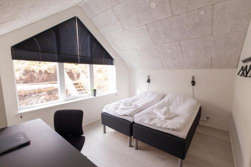 a bedroom with a bed and a desk and a window at Panorama boathouse in Klaksvík