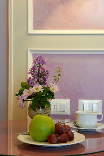 a table with a plate of fruit and a vase with flowers at Hotel Firenze Capitale in Florence