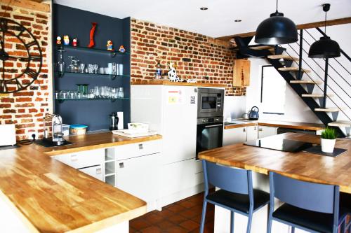 una cocina con armarios blancos y una pared de ladrillo en MAISON VIEUX LILLE 3 chambres parking privé 24H24H Accès, en Lille