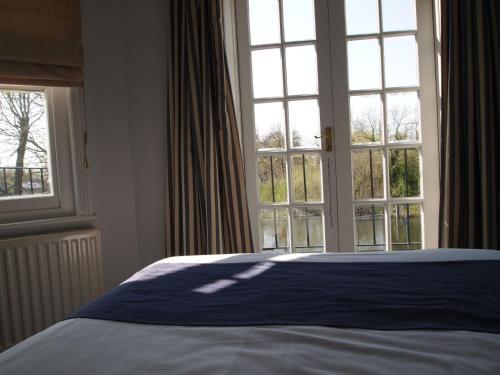 a bedroom with a bed and a large window at The Weir Hotel in Walton-on-Thames