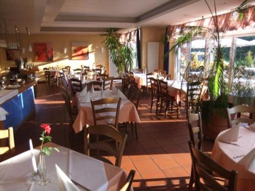 un restaurant avec des tables blanches, des chaises, des tables et un chercheur de table dans l'établissement Pension Da Enzo, à Otterbach