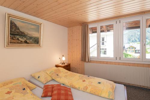 two beds in a room with two windows at Lehmann's Herberge Hostel in Grindelwald