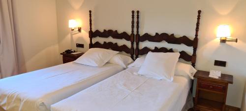 two beds in a hotel room with white sheets at Parador de Gredos in Navarredonda de Gredos