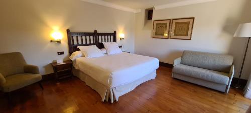 a hotel room with a bed and two chairs at Parador de Gredos in Navarredonda de Gredos