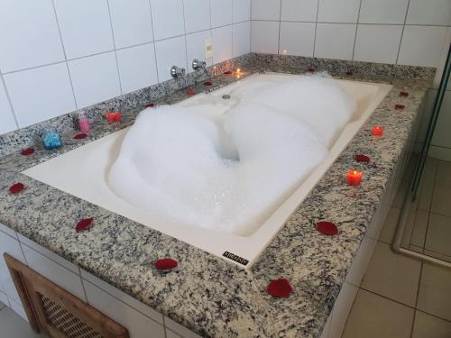 a bath tub filled with foam with red hearts around it at JC Palace Hotel in Machado