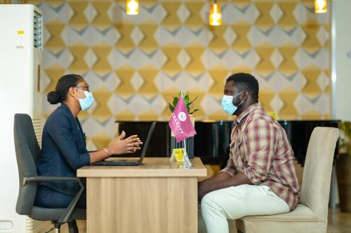 a man and a woman wearing masks sitting at a table with a laptop at Accra City Hotel in Accra