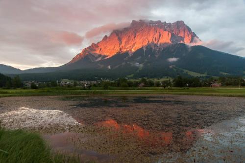 a mountain with a reflection in the water in front of it at Am Sonnenfels in Lermoos