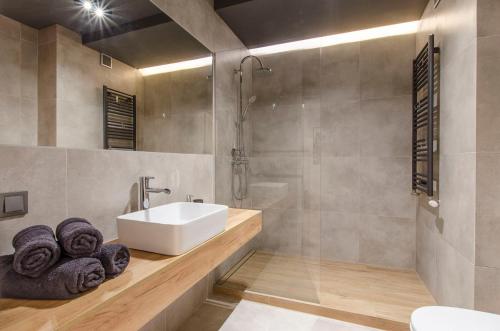 a bathroom with a sink and a shower with towels at Apartament Jarzębinowy z ogródkiem in Łódź
