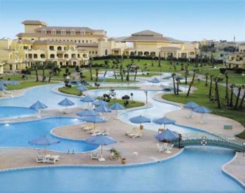 a resort with a pool of water with umbrellas at Mövenpick Hotel Cairo - Media City in 6th Of October