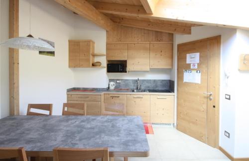 a kitchen with a table and wooden cabinets at Casa Mirandola Montana in Commezzadura