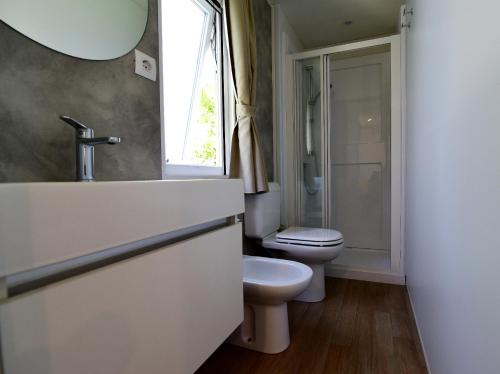 a white bathroom with a toilet and a sink at Club del Sole Adriano Family Collection in Punta Marina