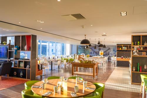 a restaurant with wooden tables and green chairs at Holiday Inn Liverpool City Centre by IHG in Liverpool