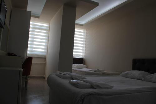 two beds in a room with two windows at Hotel Abro Necatibey in Ankara